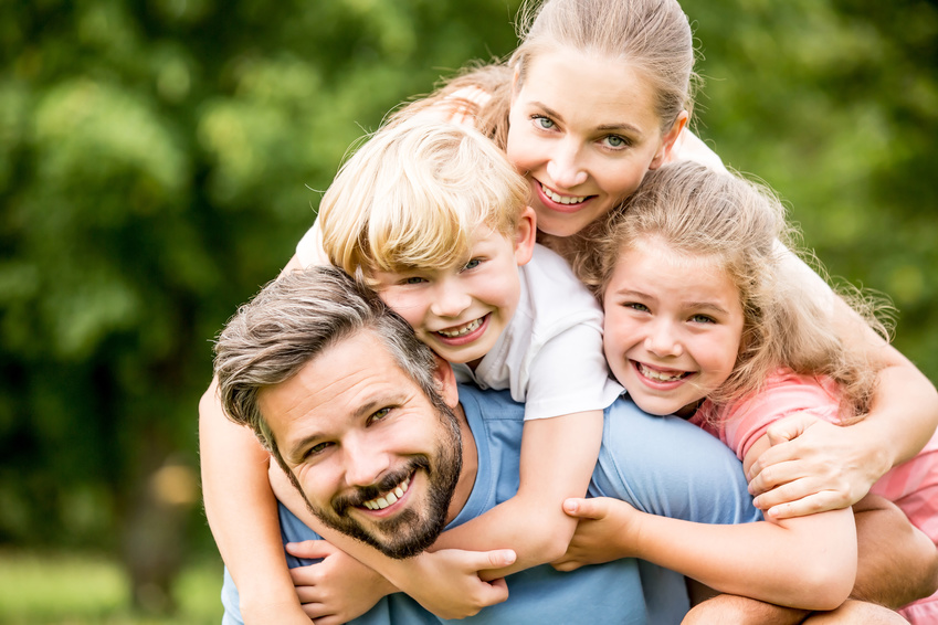 Glückliche Familie und Kinder umarmen sich liebevoll im Garten
